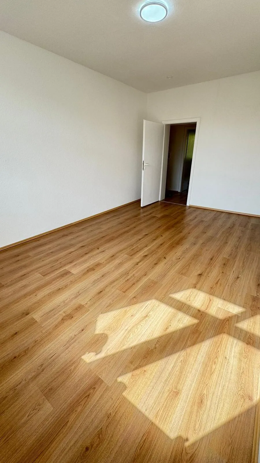 Renovierte Wohnung Dortmund: heller Wohnraum mit Eichenlaminat und Sonnenlicht. Fertig zur Schluesseluebergabe von MeisterLiga.
