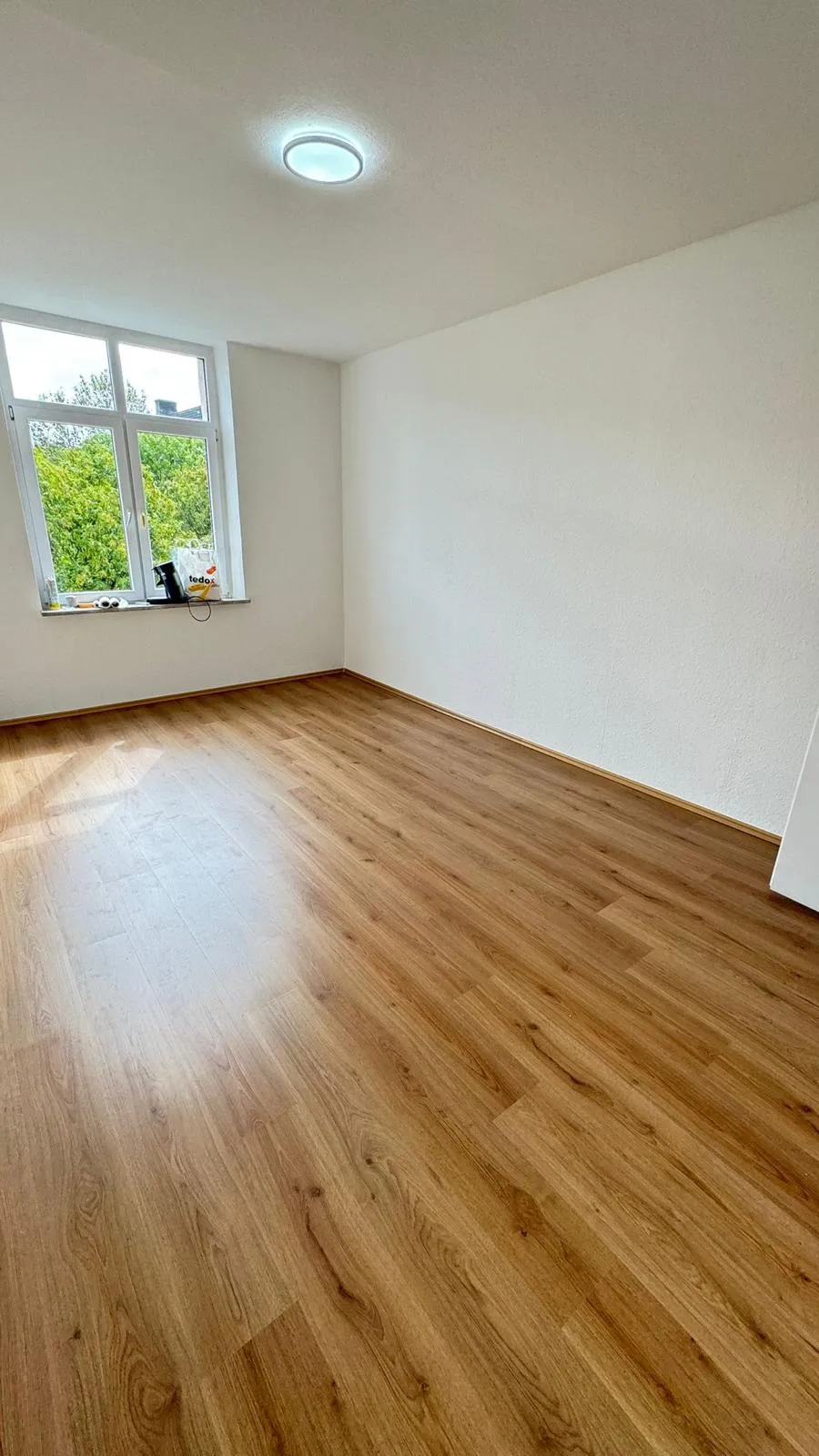 Schluesselfertige Renovierung Dortmund: helles Zimmer mit neuem Boden und Fensterblick ins Gruene. Referenz MeisterLiga.